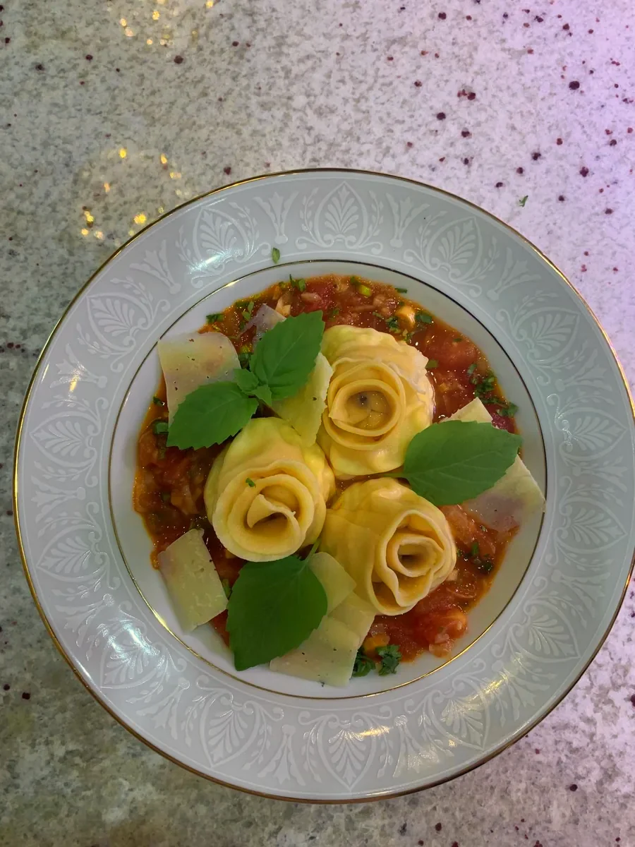 Rosas de tortellini sobre salsa de tomate con albahaca y parmesano