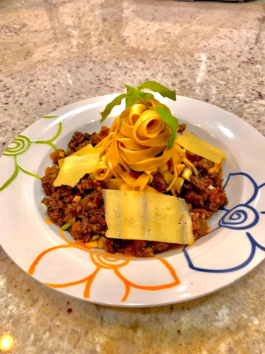 Nido de tagliatelle sobre ragú a la boloñesa con lascas de parmesano